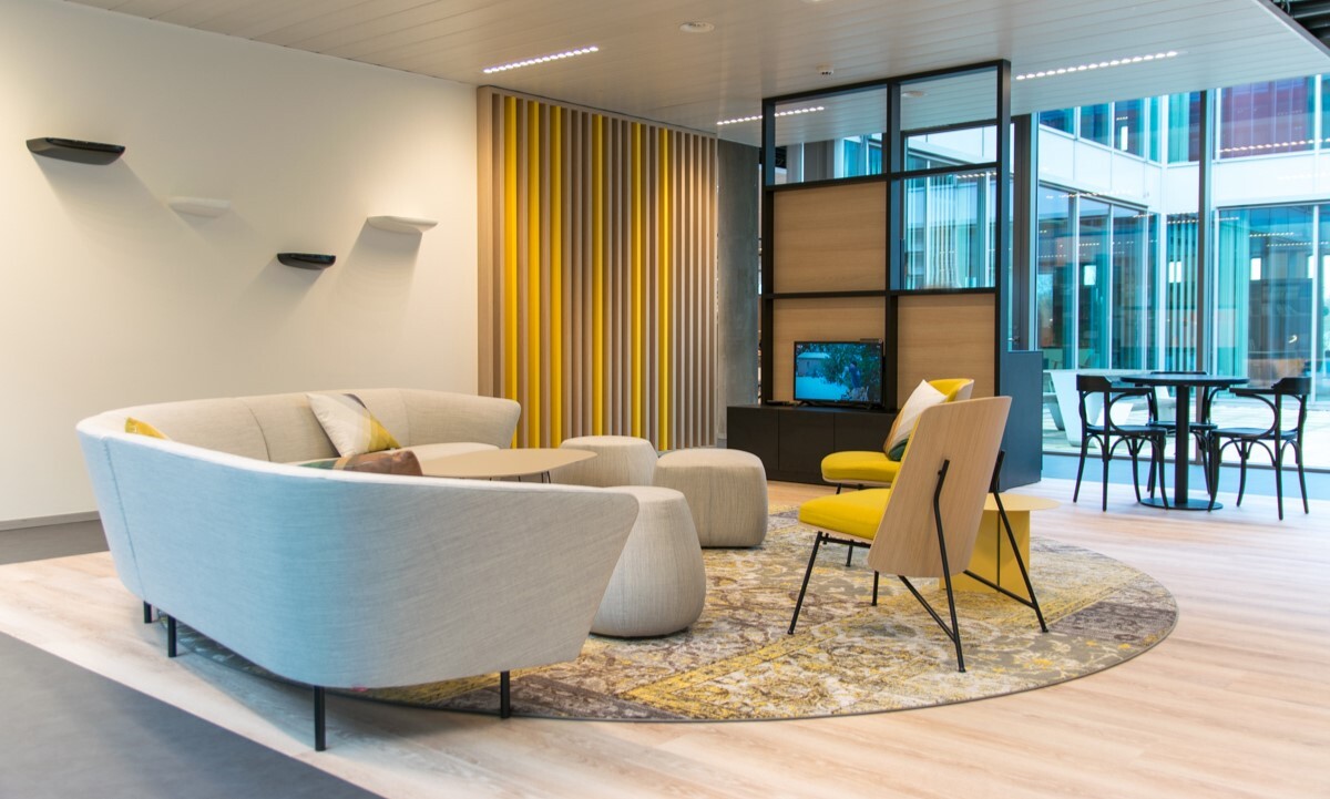 Aménagement d'un salon avec un accent jaune, un fauteuil gris et des poufs assortis