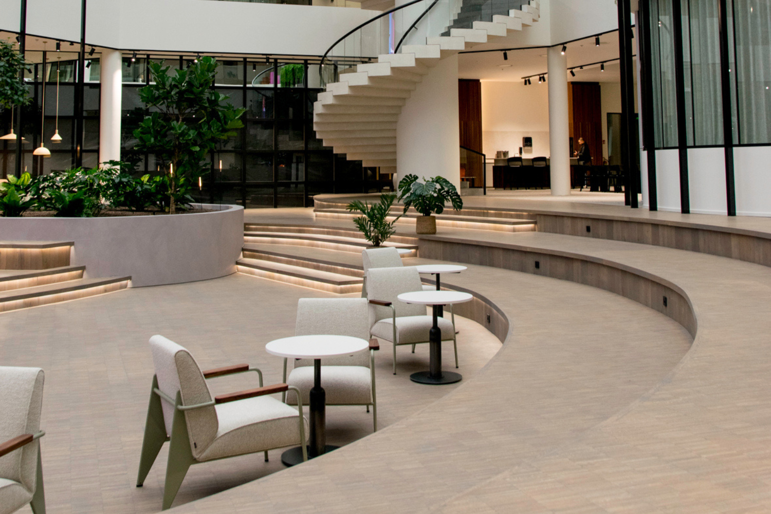 Bureau moderne et élégant avec un plan ouvert. Avec un escalier central, des bancs ronds et des tables avec des chaises.