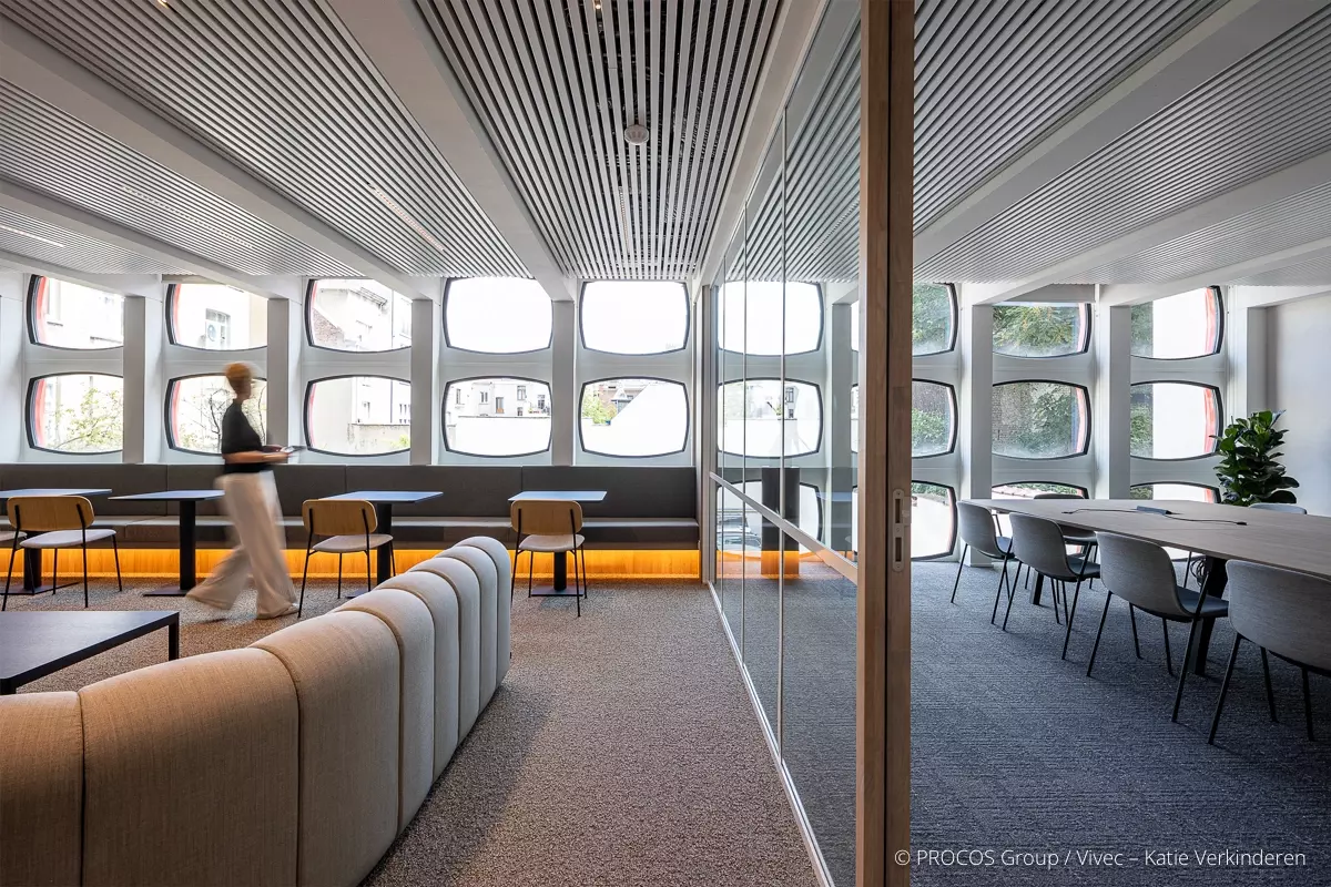 Modern office interior with an open space and a meeting room separated by a glass wall.