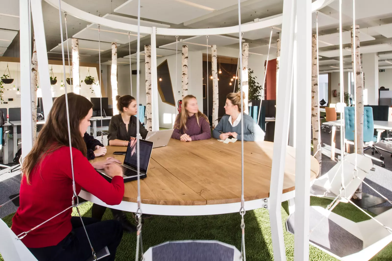 Salle de réunion avec une table ronde en bois et des sièges suspendus 