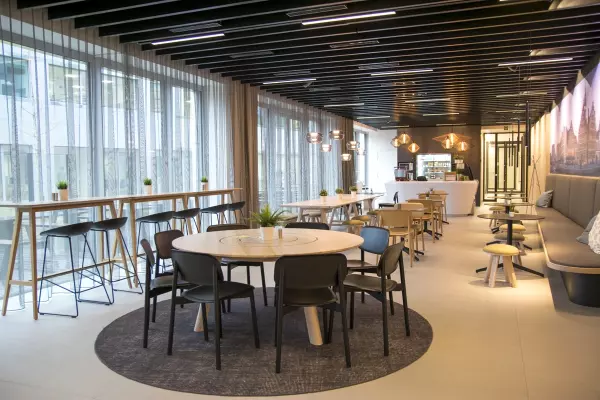 Diverses possibilités de s'asseoir : table debout avec tabourets de bar, tables rondes avec chaises et bancs de train.