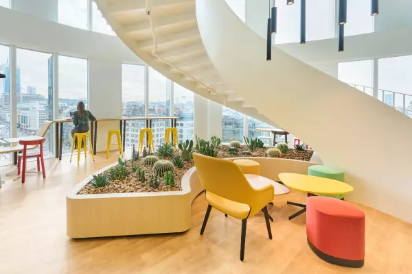 Moderne kantoorinrichting met kleurrijk meubilair, een centrale binnentuin met cactussen en grote ramen.